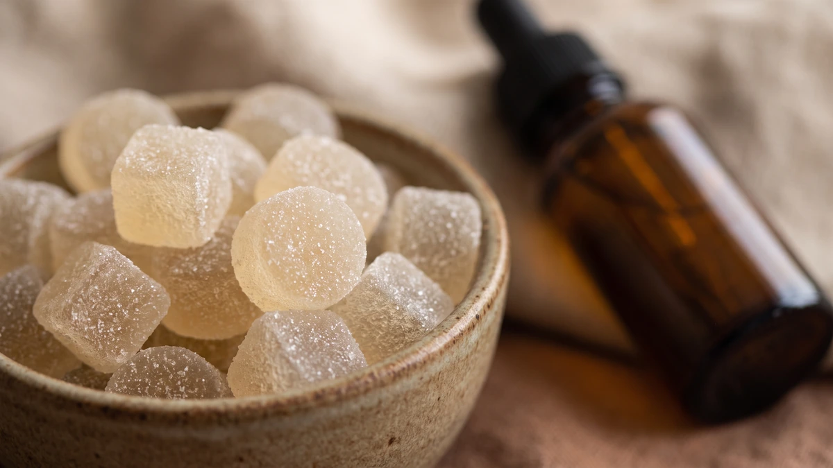 Close up of CBD gummies in a dish beside an amber dropper bottle